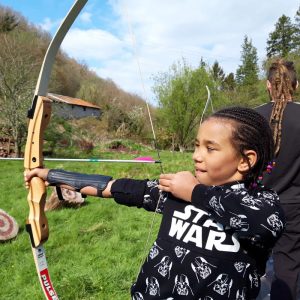 young girl aiming with her bow and arrow as she practices archery with ARC Adventures
