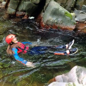 Happy girl floating in gorge. She's nervously laughing from the cold water.