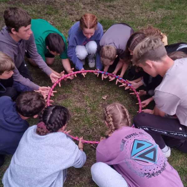group of teenagers solving a team building puzzle outside on the grass